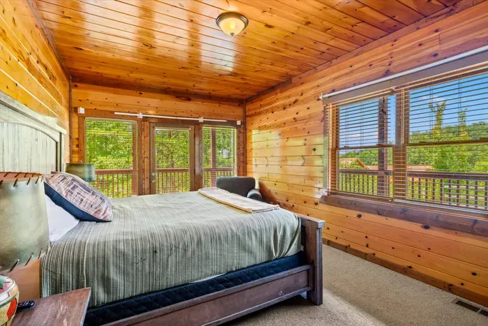 Cozy wood-lined bedroom with treetop views and private deck access