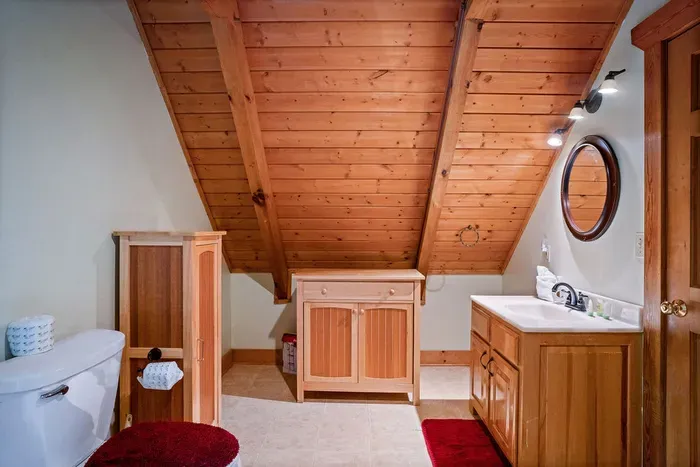 Cozy cabin-style bathroom with warm wood ceilings and extra storage