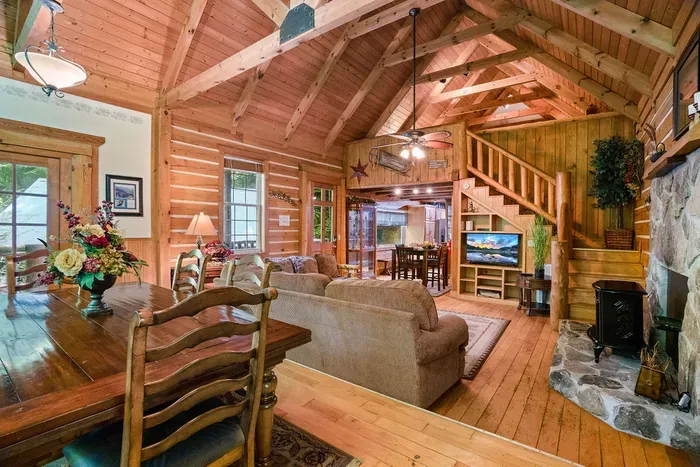 Rustic great room with vaulted ceilings, stone fireplace, and open loft