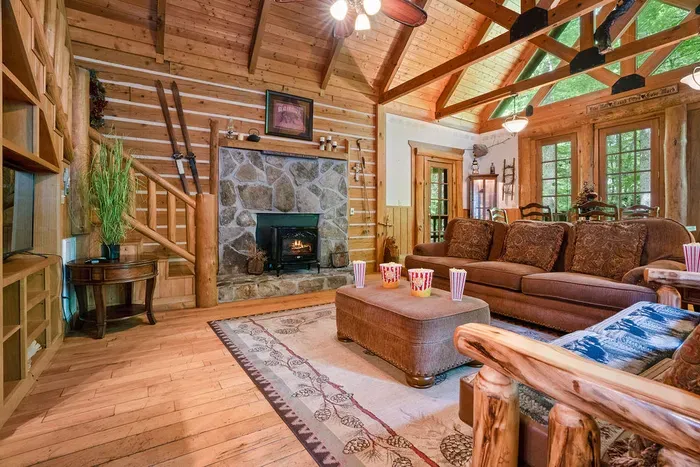 Cozy log cabin great room with stone fireplace and soaring wood ceilings