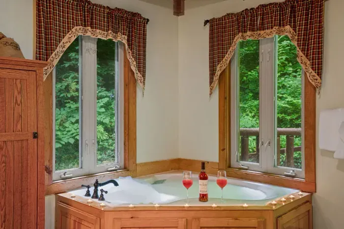 Romantic jetted tub with forest views and a cozy spa-like ambiance