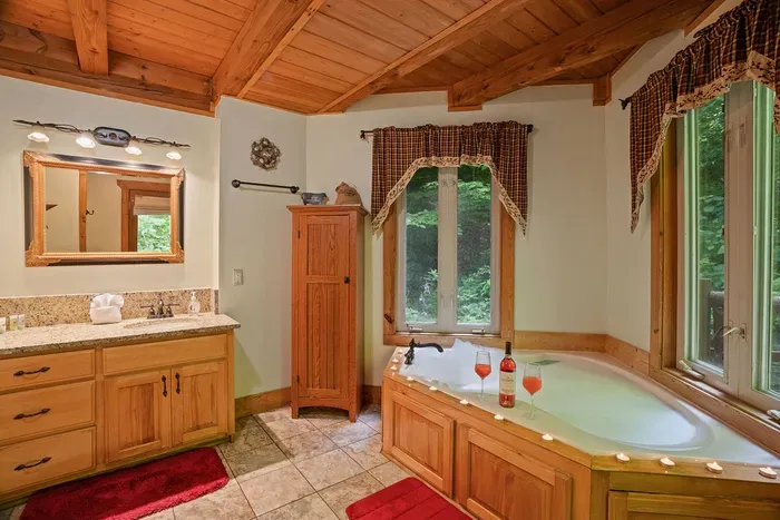 Spa-like bathroom with soaking tub, forest views, and warm rustic charm