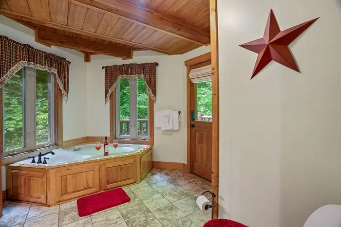 Spa-like bathroom with soaking tub, wooded views, and warm rustic charm