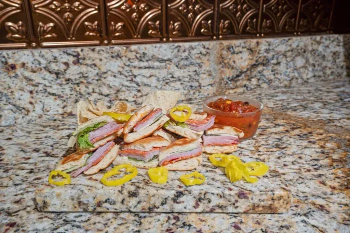 Granite kitchen counter styled with deli sandwiches and savory snacks