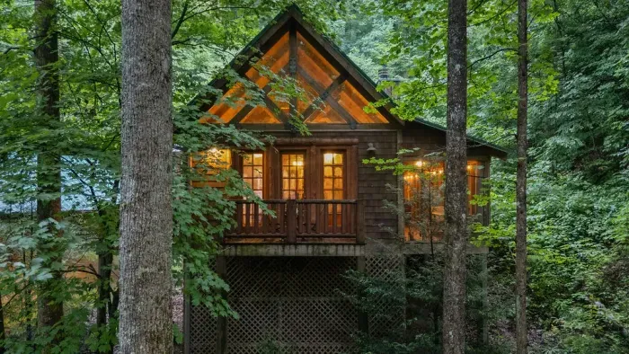 Cozy treehouse-style cabin nestled in the woods with warm, inviting glow