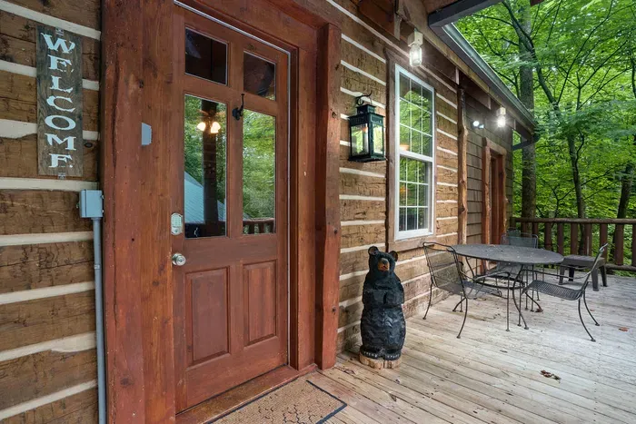 Welcoming log cabin porch with forest views and outdoor seating