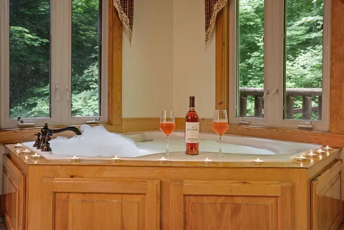 Romantic corner soaking tub with forest views and spa-like ambiance