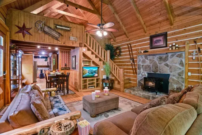 Cozy log cabin great room with stone fireplace and vaulted wood ceilings