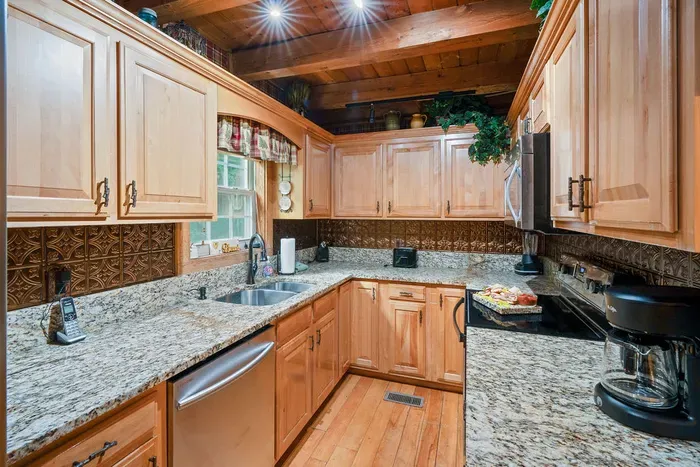 Rustic gourmet kitchen with granite counters and warm wood-beam charm