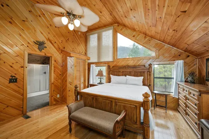 Upstairs bedroom with high ceilings, en suite bathroom, king bed, fireplace, and seating area 