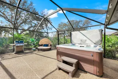 Private screened-in patio with hot tub, BBQ grill, and cozy daybed — your personal outdoor oasis.