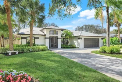 Fully updated, modern ranch-style home with lush grass, vibrant flowers, and charming palm trees.