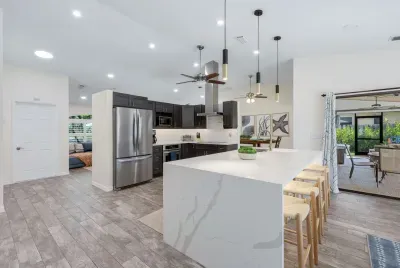 Bright, modern kitchen with a spacious island and stylish seating- perfect for cooking, quick dining, or gathering during your stay.