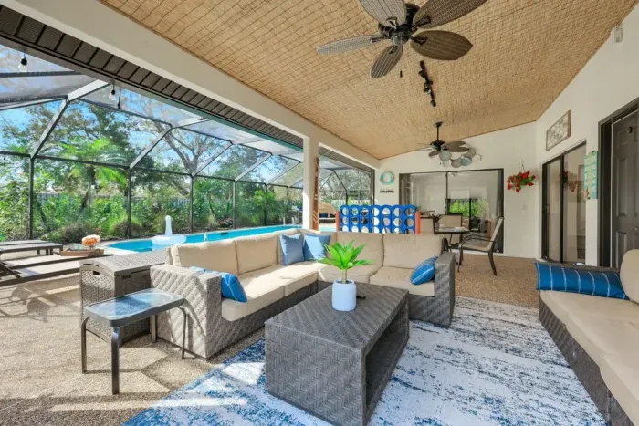 Tropical lanai with ample seating, outdoor TV, and fun vibes featuring a giant Connect 4 game.