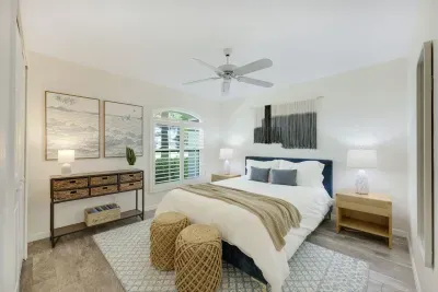 Inviting guest bedroom with a queen bed, elegant plantation shutters, and a full-length mirror for added style.