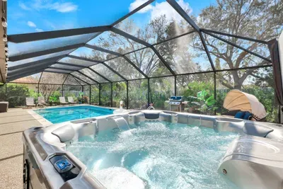 Relaxing hot tub and pool in a private screened enclosure, complete with a cozy daybed for ultimate relaxation.
