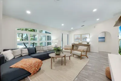 Step into a bright, welcoming living space featuring cozy seating, chic coastal décor, and natural light pouring through plantation shutters. Perfect for relaxing with a book or gathering with loved ones after a day of adventure.