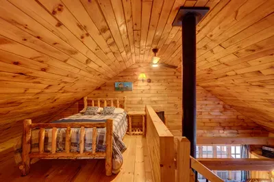 Perched above the main living space, the loft offers a cozy queen bed under warm wood ceilings.