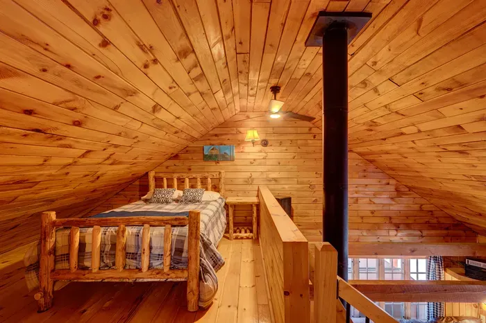 Perched above the main living space, the loft offers a cozy queen bed under warm wood ceilings.