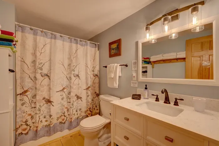 Updated bathroom with a spacious shower, fresh towels, and warm lighting for a relaxing reset.