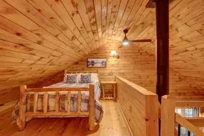 Perched above the main living space, the loft offers a cozy queen bed under warm wood ceilings.