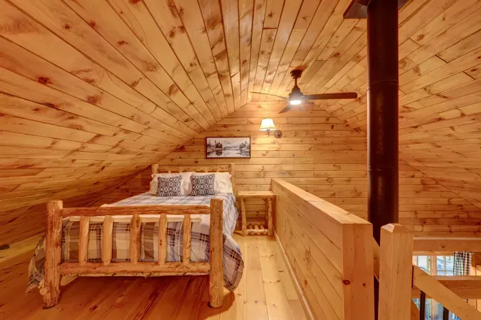 Perched above the main living space, the loft offers a cozy queen bed under warm wood ceilings.