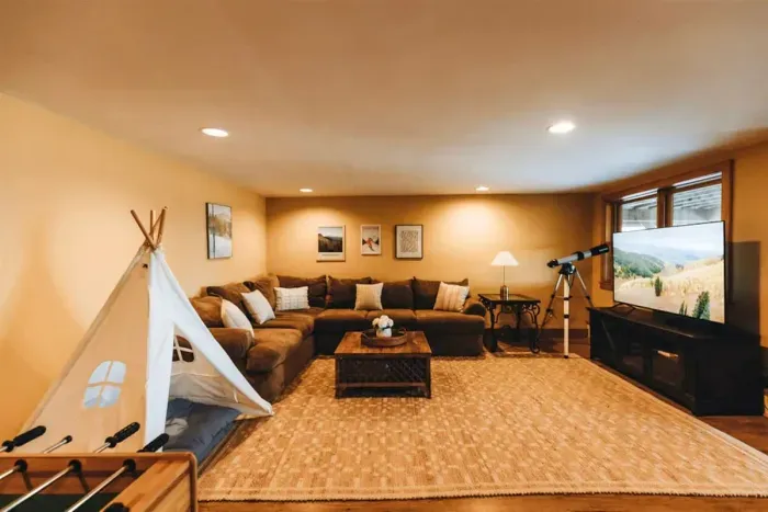 The lower level family room / game room features a large sectional sofa, football table, pingpong table, a 65" TV, a telescope for star gazing... and even a teepee for the kiddos