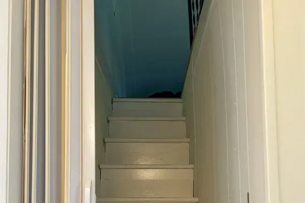 Stairs leading up to the bonus room for kids, with 3 twin beds. Note the steep, narrow staircase and accordion door. 