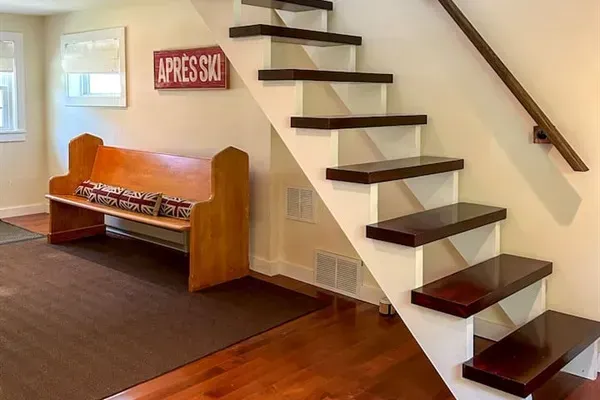 Entryway and stairway leading up to the primary bedroom suite. Please note that the stairs are open on one side, so young children should not go up or down the stairs without an adult. 