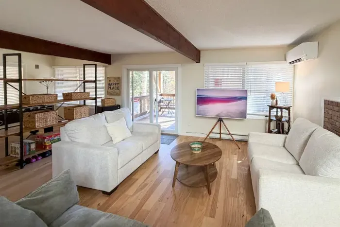 Living area on the ground floor with a TV, games, puzzles, and foosball table. The two white loveseats are twin pullouts. 