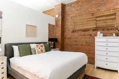 Bedroom area with lots of clothing storage. Beauty Rest king bed, high ceilings and lovely brick walls.