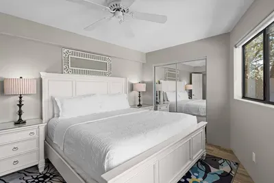 [Bedroom 3] Downstairs king bedroom with direct access to the lower level deck with hot ub.features a crisp white king bed frame, ceiling fan, and mirrored closet.