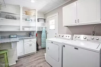 Laundry room with full size washer, dryer, iron, and ironing board.