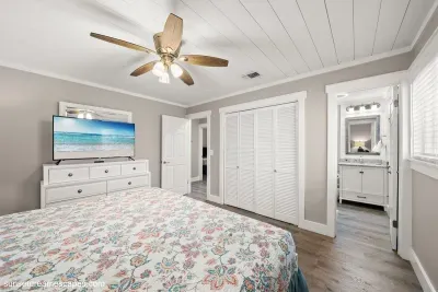 Relax in the primary bedroom with King bed, television, en suite bathroom, and access to the back porch and pool. 