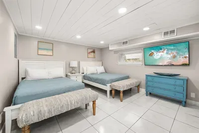 With two full beds, this hall bedroom downstairs can accommodate up to 4 guests. A 55" Roku-enabled TV is available for entertainment, with benches at the foot of each bed.