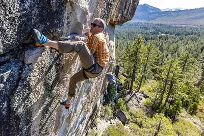a man rock climbing on granite performing a heel hook manuever