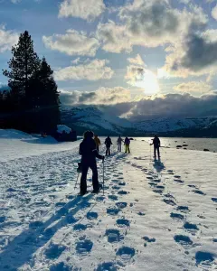 a few snowshoers walking in the snow with a beautiful sunset.