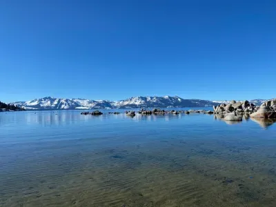 A view of the Lake Tahoe in the winter with snow capped mountains in the distance.