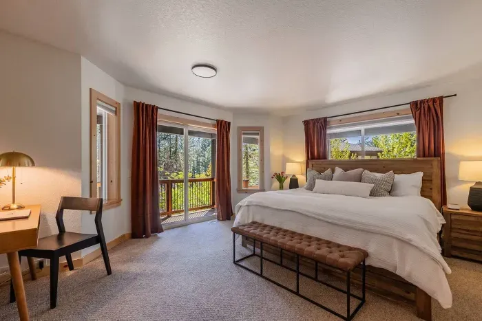 Views into our primary suite, located on the main level. This room features a comfortable King size bed, work area, walk in-closet and ensuite bath. The sliding glass door leading to a covered deck and the hot tub area is to the right.