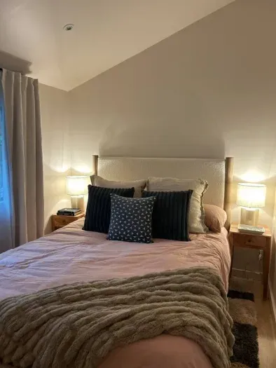 One of two bedrooms on the main level of the house, this room has vaulted ceilings, a queen bed with high quality bedding, and a large window that overlooks the backyard