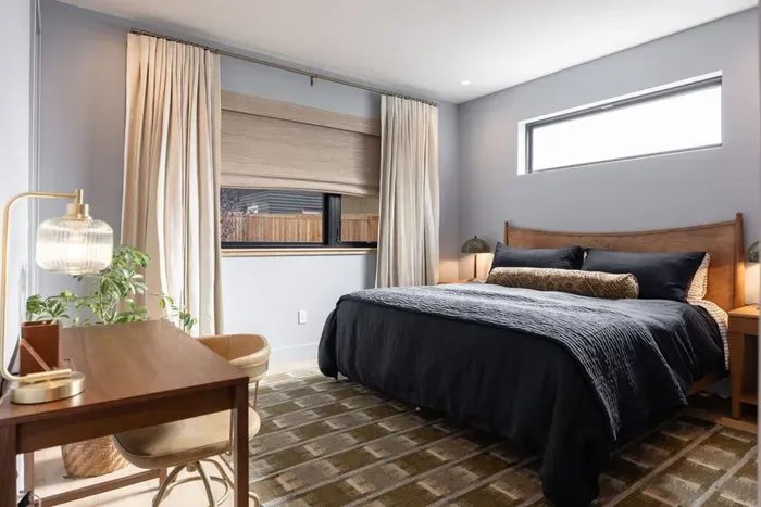 Extra spacious primary bedroom located on the ground level, complete with king bed, desk, blackout curtains, ensuite bath, and walk-in closet.