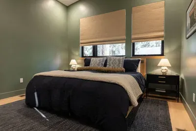 Sleep with in the second primary bedroom at The Lake Trail Lodge. King-sized bed, cotton and linen bedding from Quince and ultra comfortable new mattresses and pillows. The ensuite bath with walk-in shower and double vanity is just to the right.