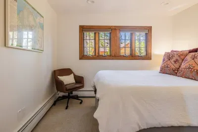 This is bedroom #4, which features a queen-sized bed and is located at the turn in the  L-shaped hallway.
