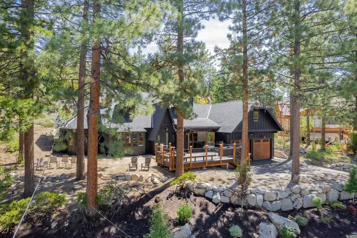 The home is set on a small elevated knoll surrounded by pine trees, providing privacy and a forest-like setting. 