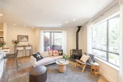 All furnishings have been updated in the living room, and it has easy access to both the kitchen and the small covered patio, which is just visible behind the sofa.