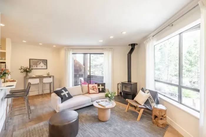 All furnishings have been updated in the living room, and it has easy access to both the kitchen and the small covered patio, which is just visible behind the sofa. 