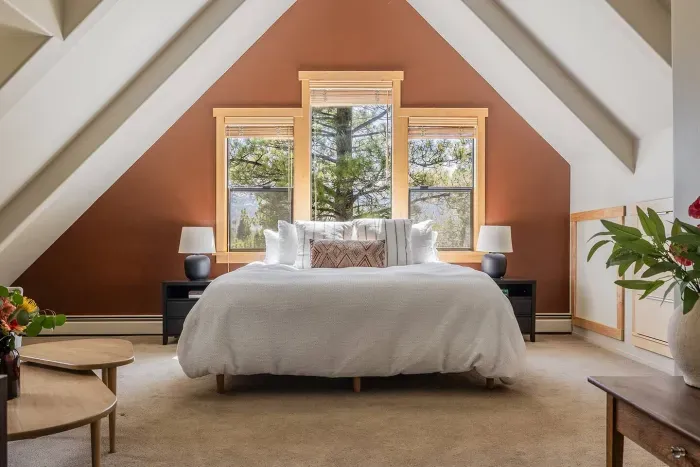 The spacious primary bedroom, located upstairs,  features an ensuite bathroom, seating area, large flat screen TV, walk-in closet plus forest and mountain views. In warmer months, we install a window unit AC to keep this room cool and comfortable.
