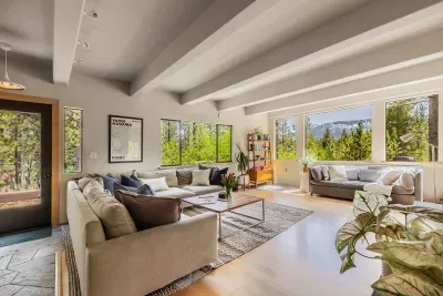 Our spacious living room has mountain and forest views from every angle plenty of comfortable seating. The front door of Echo View Chalet is visible just to the left.