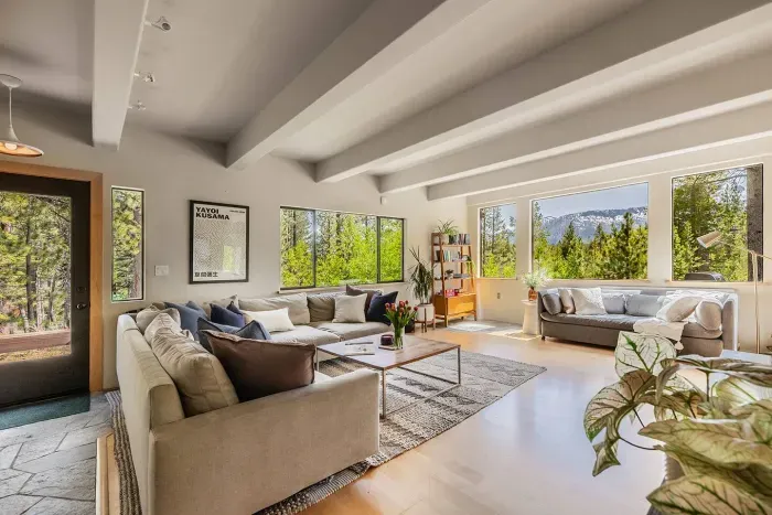 Our spacious living room has mountain and forest views from every angle plenty of comfortable seating. The front door of Echo View Chalet is visible just to the left.