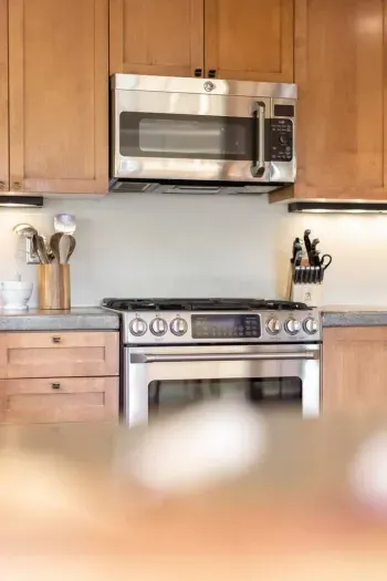 The kitchen features a four burner gas range with griddle and microwave oven.